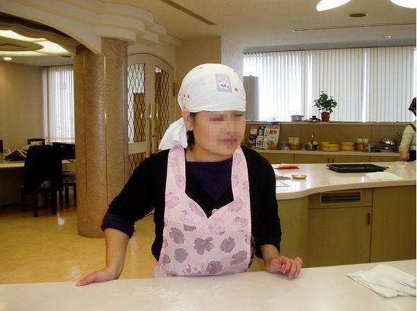エプロンと三角巾で準備万端のあきがテーブルの前に立っている写真